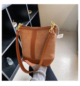 Detailed view of the brown spliced suede and leather bucket bag with gold hardware