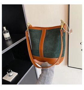 Detail showing contrast stitching and dark green matte texture of the bucket bag