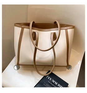 Close-up of cream and brown tote bag with high-quality leather texture on a white chair