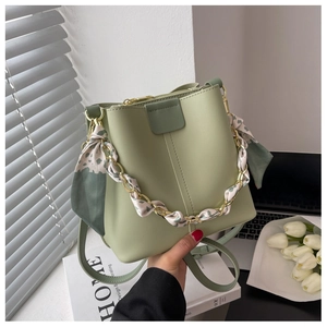 Detail of light green bucket bag with silk scarf wrapped chain and faux leather texture