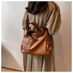 Sac bandoulière marron vintage avec poche zippée porté par un mannequin en trench-coat