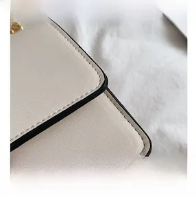 Detail of beige faux leather texture with clean black oil edge finish and gold chain
