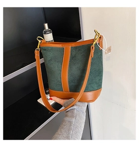 Detail of vintage bucket bag with green suede and brown leather trim held by hand