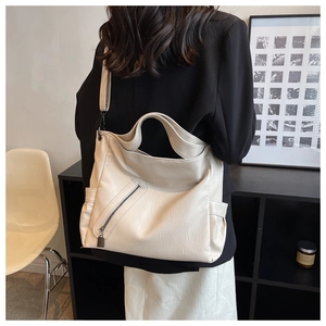 Détail du grand sac cabas crème avec large bandoulière porté par un mannequin