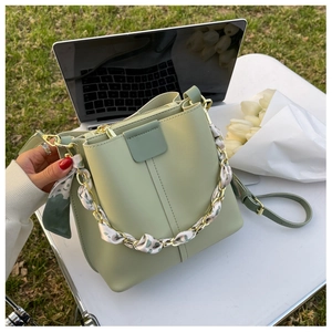 Detail of light green bucket bag featuring a silk scarf wrapped gold chain handle