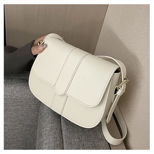 Detailansicht der cremeweißen Satteltasche mit feinen Nähten und goldenen Beschlägen
