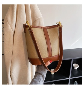Detail of two-tone bucket bag featuring beige lychee texture and brown leather trim