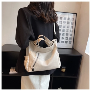 Détail d'un grand sac cabas beige en cuir souple porté par un mannequin en tenue chic