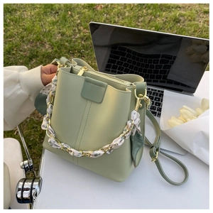 Detailed view of light green leather bucket bag with silk scarf handle and gold chain details