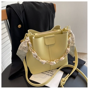 Detailed view of yellow bucket bag with silk scarf chain and adjustable shoulder strap