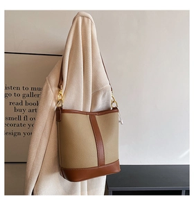 Detail of khaki and brown bucket bag showing lychee grain leather and gold hardware