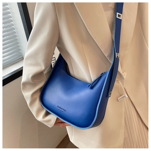 Detail of royal blue crescent shoulder bag featuring fashion bag NEW YORK logo text