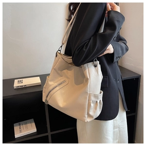 Grand sac hobo crème avec fermeture éclair et large bandoulière porté par un mannequin