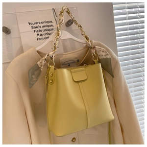 Detail of cream bucket bag with elegant silk scarf wrapped chain handle and stitching