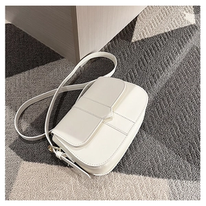 Detailansicht der cremeweißen Leder-Satteltasche mit V-Ziernaht und goldener Hardware