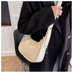 Detail of cream crescent underarm bag in smooth leather on a model wearing black