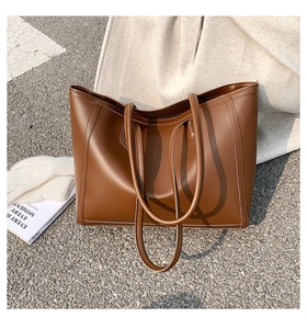 Close-up of brown tote bag showing smooth synthetic leather texture and fine stitching detail