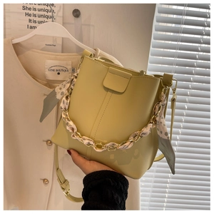 Detail of yellow bucket bag with chunky gold chain and polka dot scarf accessory