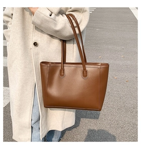 Deep brown matte leather tote bag shown on model in a stylish street style shot