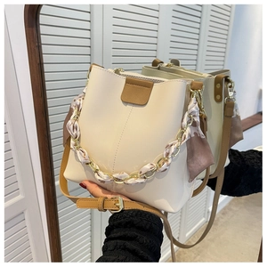 Detail of cream bucket bag with silk scarf handle and leather trim reflecting in a mirror