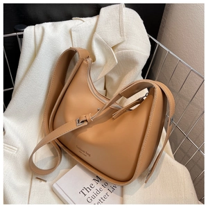 Detail showing the tan crescent shoulder bag with minimalist fashion bag New York lettering