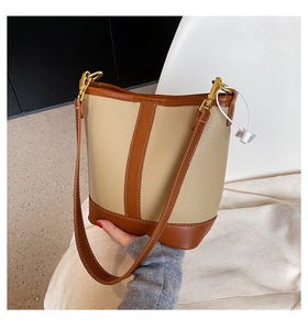 Detail of contrast stitching and golden hardware on the beige leather bucket bag