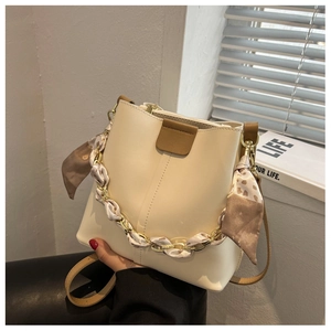 Detail of cream bucket bag featuring silk scarf wrapped chain and brown leather trim