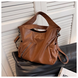 Détail du cabas marron foncé sur canapé en cuir avec zip frontal et bandoulière large