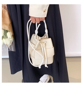 Close-up of cream woven bucket bag featuring thick rope drawstring and texture