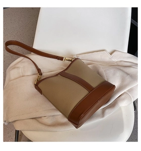 Detail of color-block bucket bag in brown leather placed on a stylish blazer