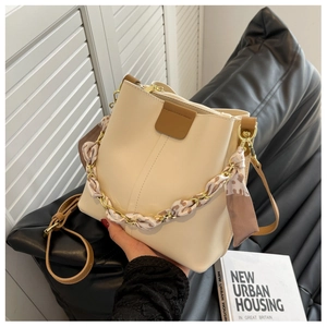Beige bucket bag detail showing silk scarf wrapped chain handle and brown PU leather accents