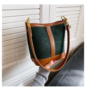 Close-up of retro bucket bag in green suede and brown leather with gold buckle