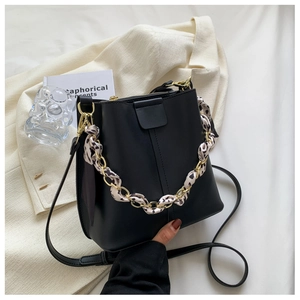 Detail of black leather bucket bag featuring a gold chain handle and leopard print scarf
