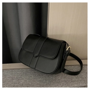 Seitenansicht einer minimalistischen schwarzen Satteltasche mit goldenen Beschlägen und Mattleder