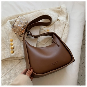 Detail of dark brown leather crescent bag with NEW YORK text on white tweed coat