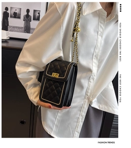 Detail of black quilted crossbody bag with gold bead trim and metal chain strap