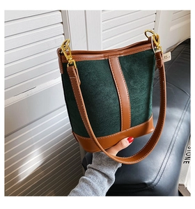 Detail of green suede bucket bag with brown leather contrast and gold hardware
