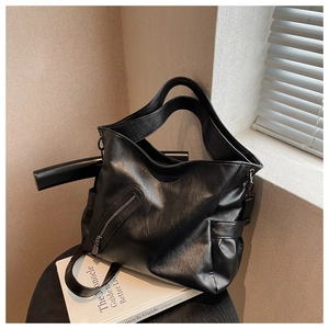 Détail du grand sac cabas en similicuir noir avec poche latérale sur un tabouret moderne