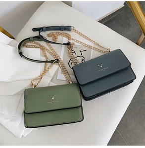 Detail of crossbody bags with golden deer logo and metal chain straps on white surface