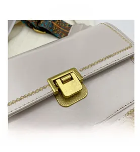 Détail de la boucle en métal doré et broderie d'étoiles sur le sac bandoulière en cuir beige