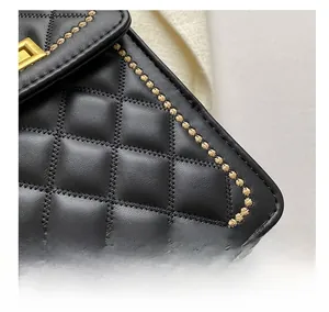 Macro shot of black quilted leather with gold embroidery and metal buckle details