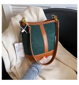 Detail of green suede and brown leather bucket bag with gold ring buckle and secure piping