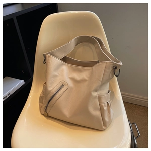 Détail d'un grand sac en similicuir crème avec large bandoulière sur une chaise design