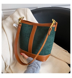 Detail of dark green suede bucket bag with brown leather trim and gold metal hardware