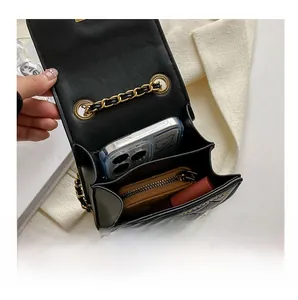 Interior detail of a black quilted shoulder bag showing phone, wallet and lipstick capacity