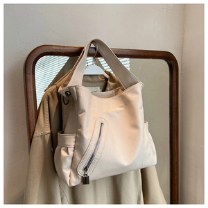 Détail d'un sac cabas beige avec poche zippée diagonale et texture en cuir souple
