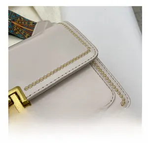 Détails de sac en cuir beige avec boucle dorée et bandoulière à motifs géométriques