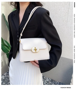 Vue latérale d'un sac à rabat en cuir crème avec fermoir doré porté par un modèle