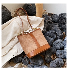 Detail of vintage suede bucket bag with contrast stitching and golden hardware accents