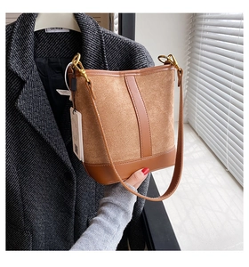 Detailed close-up of brown suede bucket bag with leather accents and gold hardware hooks
